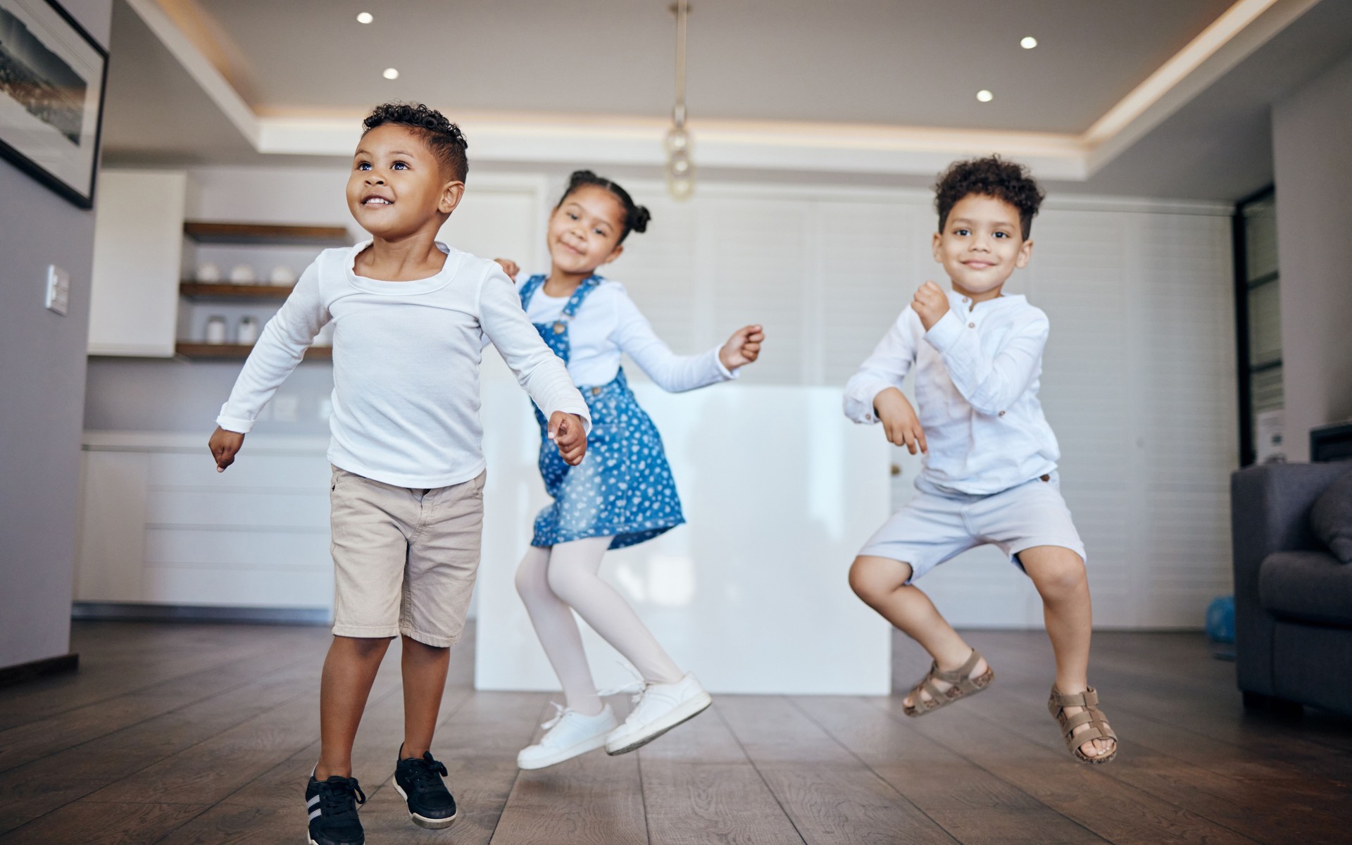 Family, children and siblings dance in a house with energy, moving and music at home together. Love, freedom and kids in living room for fun jump games, bond and celebration of vacation or weekend